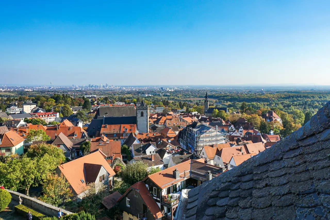 Luftbild über die roten Dächer der Altstadt mit Kirchturm und Skyline am Horizont