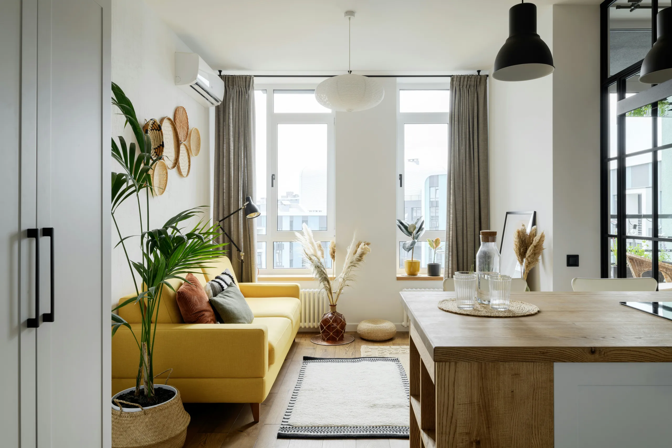 Wohnbereich mit gelbem Sofa, Zimmerpalme und Küchentheke aus Holz