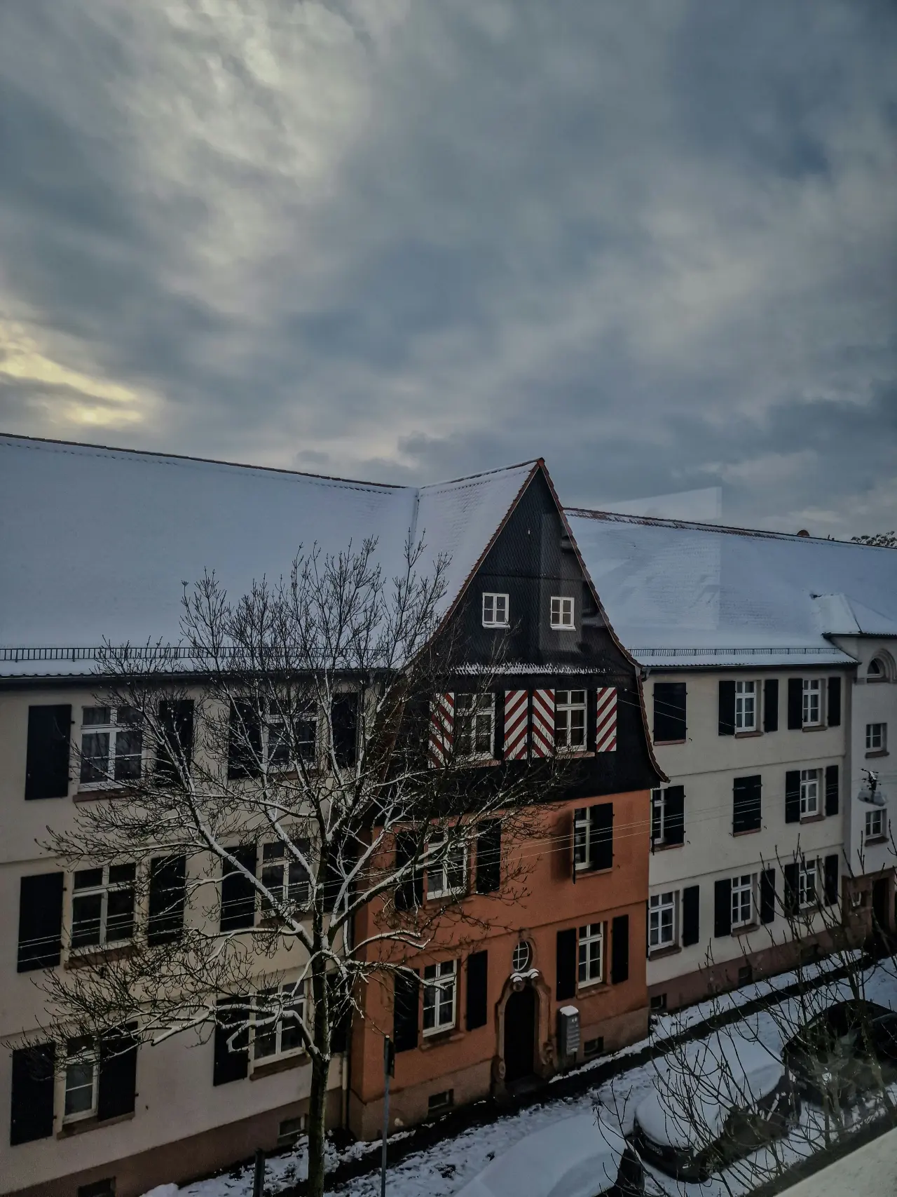 Historisches Haus mit rot-weißem Fachwerkgiebel und schneebedeckten Dächern im Winter in Hanau