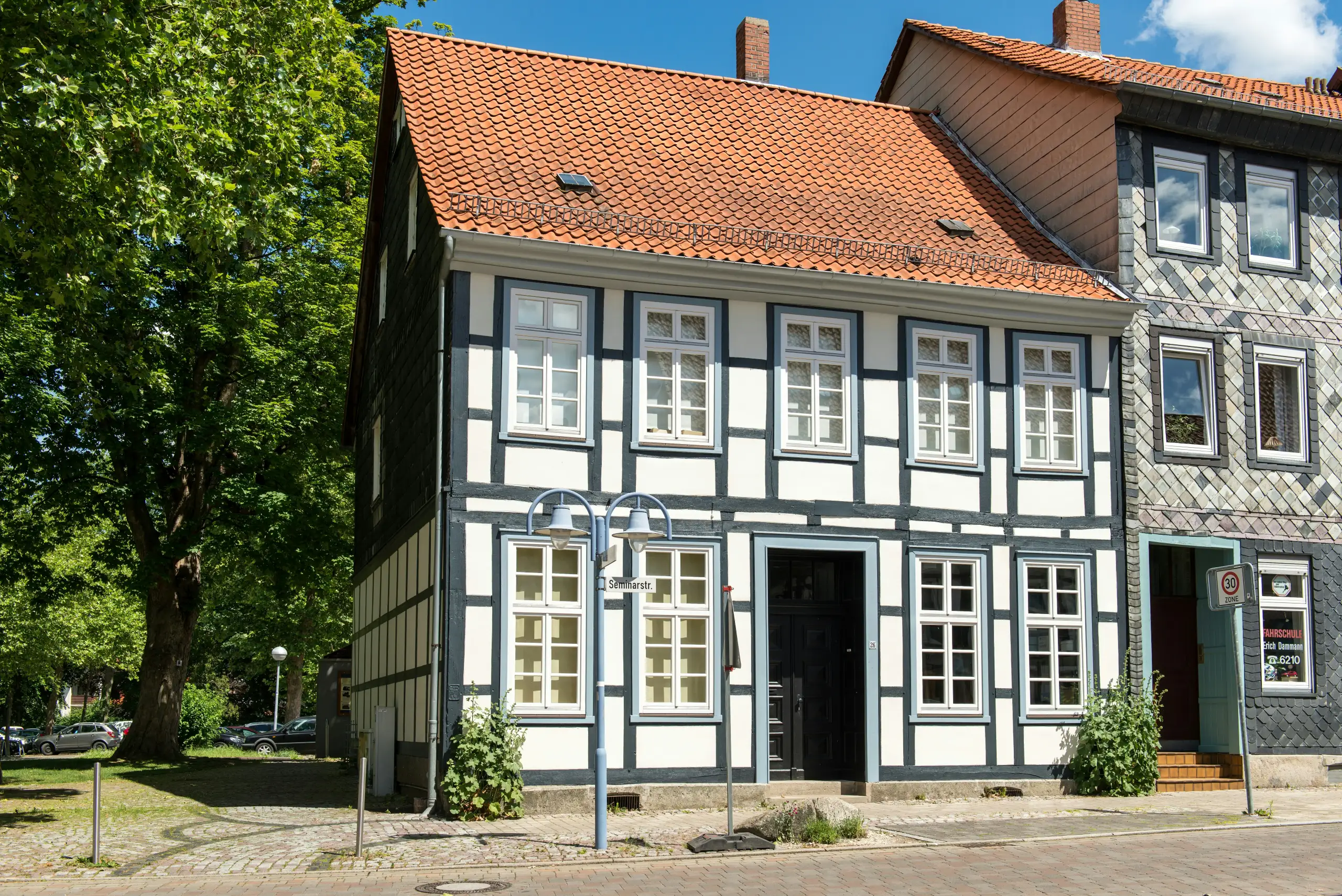 Fachwerkhaus mit grauem Gebälk und rotem Ziegeldach an der Straßenecke