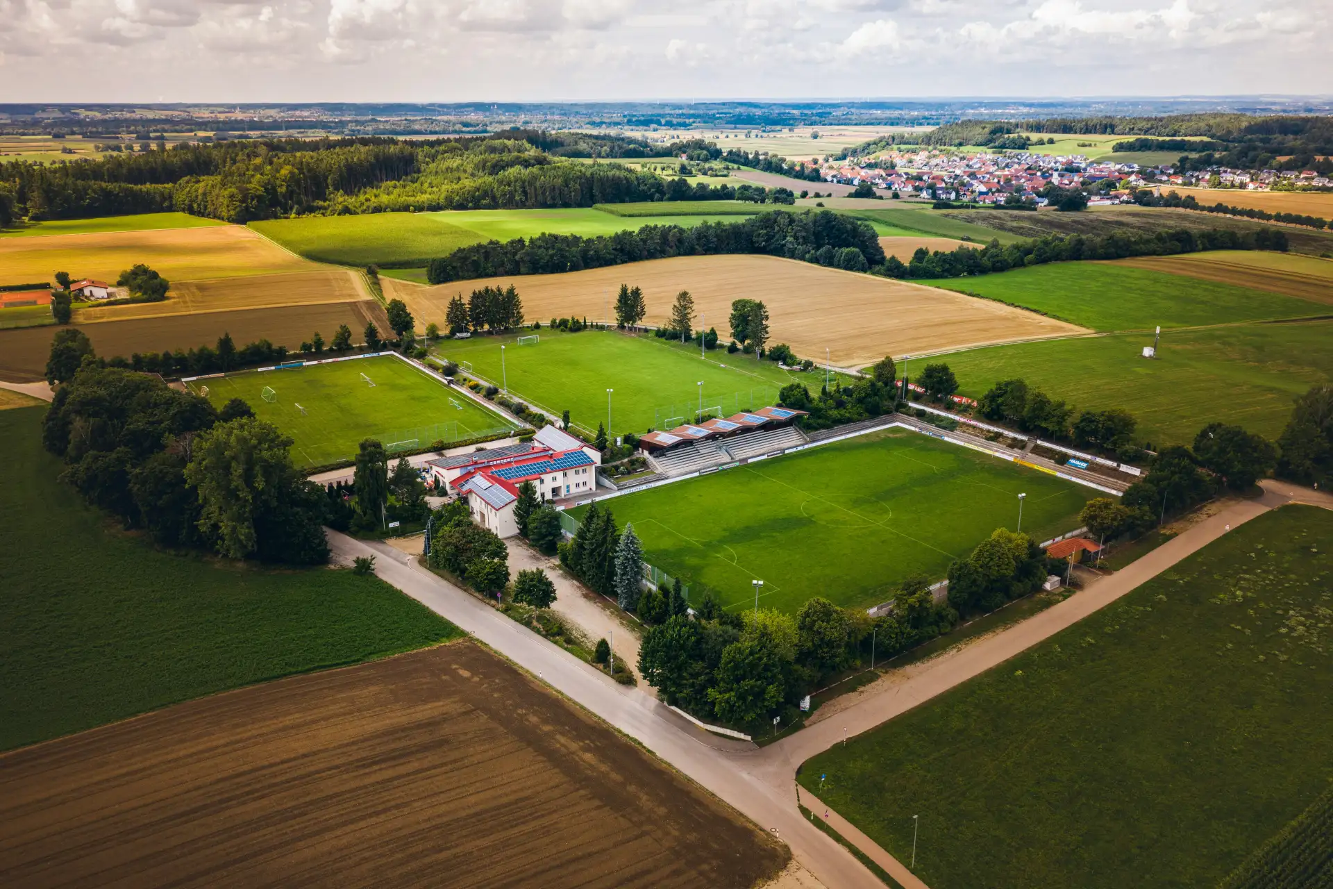 Luftbild eines Sportgeländes zwischen Äckern und Feldern