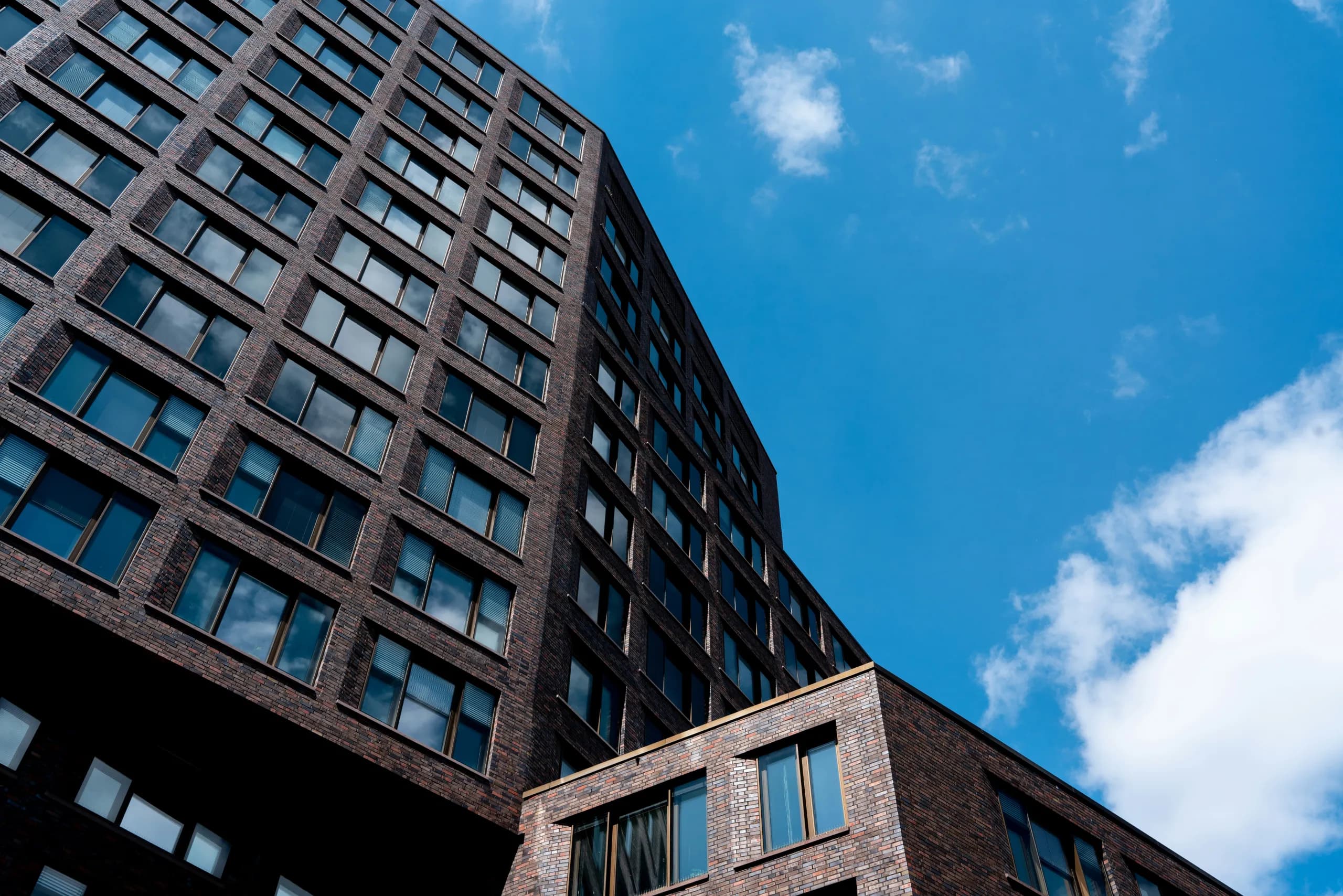 Büroturm mit dunkler Klinkerfassade vor blauem Himmel