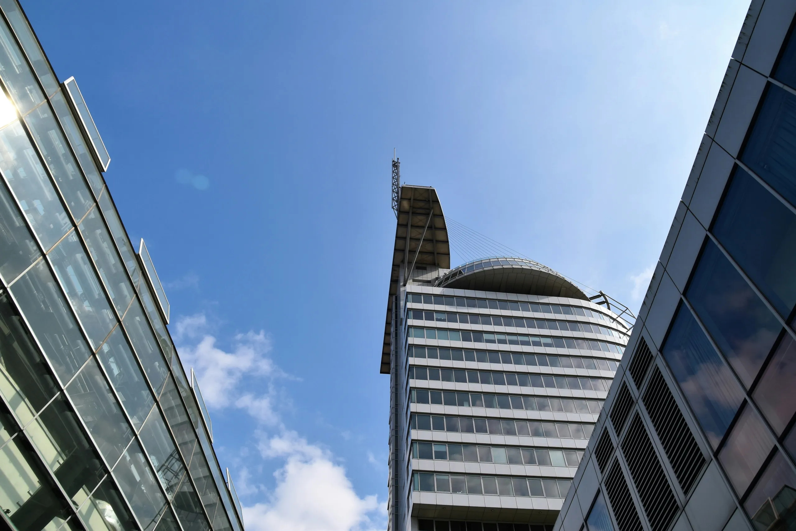 Büroturm mit geschwungenem Dachsegel zwischen Glasfassaden
